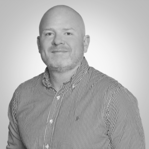 Head-and-shoulders portrait of a bald man with light facial stubble, wearing a striped button-down shirt.